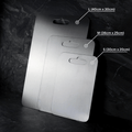 Three grey metal cutting boards with rounded corners and hanging handles