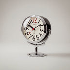 Round analogue alarm clock with bold numerals and raised metallic-effect stand