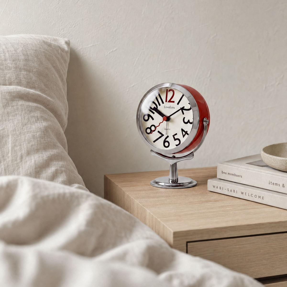 Round analogue alarm clock with bold numerals and raised metallic-effect stand