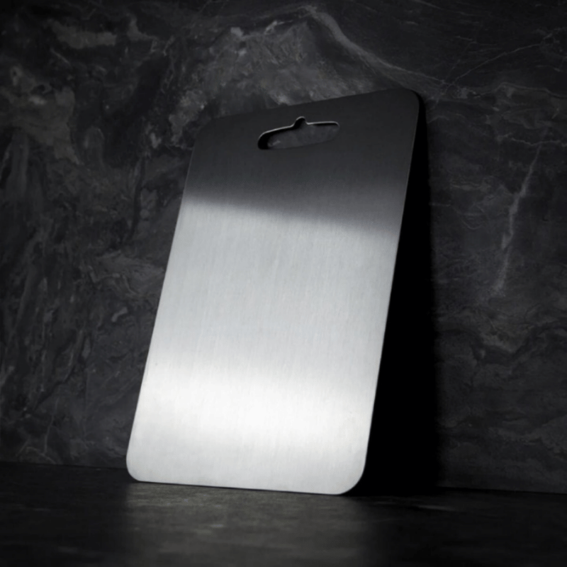 Three grey metal cutting boards with rounded corners and hanging handles