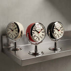 Round analogue alarm clock with bold numerals and raised metallic-effect stand