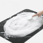 Black rectangular bathroom mat with white marble-effect veining and rounded corners