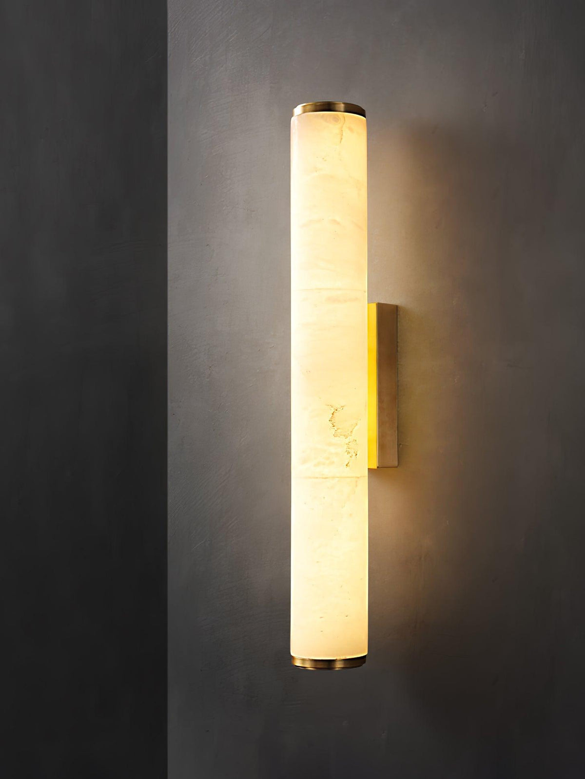 Vertical alabaster column wall sconce emitting warm light