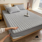 Quilted mattress protector with a padded square design on a bed