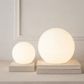 Spherical cordless LED table lamp glowing with coloured light