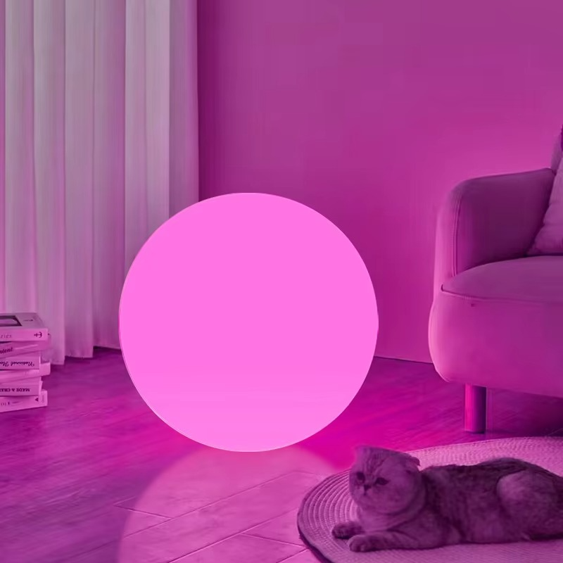 Spherical cordless LED table lamp glowing with coloured light