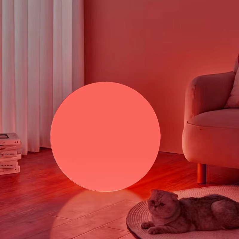Spherical cordless LED table lamp glowing with coloured light