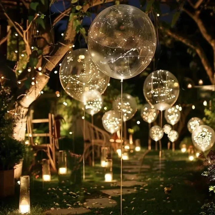 Clear LED balloons with warm white string lights along a garden path