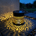 Black cylindrical solar mandala projector light casting a patterned glow outdoors