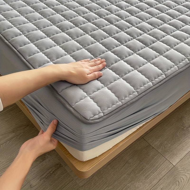 Quilted mattress protector with a padded square design on a bed