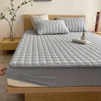 Quilted mattress protector with a padded square design on a bed