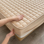 Quilted mattress protector with a padded square design on a bed